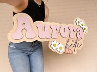 PLEASE visit our website to create a mock-up of your sign! ➡️ www.twoavocadossigns.com Please write your design ID in the personalization box at checkout. 🥑 LISTING SIGN INFO Fonts - Lovely / Autumn Colors - Retro Pink Golden Pecan Flowers in White and Mustard 🥑 DETAILS  -These signs have ¼" letters painted to your selected color and attached to a ½" birch wood backer that can be natural wood, stained, or painted white.   -You can order either just a first name only, or a first and middle name for this listing!   -The sign comes exactly as pictured with the same image on the sign.  -Every element of your sign is customizable concerning color and font. If the font and/or color is not specified, we will default to the same ones as shown in the main listing photo.  -The sides of the letters