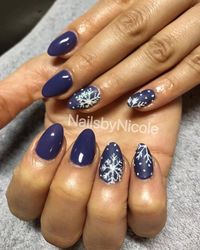 These deep midnight blue nails capture the mystery and beauty of a winter’s night. The almond-shaped acrylic nails are adorned with fine white snowflakes on the middle and ring fingers, adding an elegant, wintry touch. This dark, rich color combined with the delicate white accents makes for a sophisticated yet bold winter manicure, perfect for formal events or cozy nights by the fire.