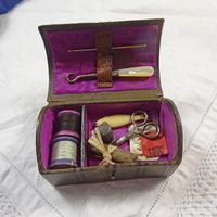 Charming little Victorian sewing box with contents, possibly for a doll or for a child. The box is shaped like a travelling trunk, with a domed lid.  It is covered in dark brown leather, with embossed lines and metal studs in the top, and a leather carrying loop on the top. Closes with a pretty gilt metal clasp.  Brown paper covered base.   Probably dates to late 19th or early 20th century. Box size approx. 3" x 2.75" x 2.75 tall" (8 x 4.5 x 4.5 cm).  Inside is lined in the original purple silk,