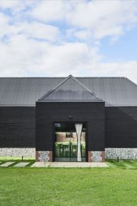 The double height glass doors sit within the large doorway of a barn conversion. The award winning project - shortlisted for the Manser Medal - turned a black clad barn into a modern home. The double height glass doors bring in light and help connect to the outdoors. Click the image to see the full case study. 