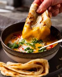 Dunking roti into Thai Coconut Pumpkin Soup