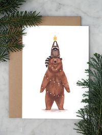 Cute Christmas card with illustration of a bear and a raccoon trying to be a Christmas tree. Text on the back: Happy Holidays Also available per set of 10 here: https://www.etsy.com/listing/1813729850/ Details: A6 size, 105 x 148 mm Single postcard Full color print on heavy weight textured paper Including recycled envelope in brown craft paper