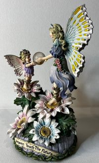 This beautiful music box from the San Francisco Music Box Co. features a charming adult fairy and child fairy design that will add a touch of magic to any collection. Crafted in China and manufactured in the modern era, this collectible is perfect for those who appreciate both whimsy and quality. With its delicate details and enchanting melody, this music box is sure to delight all who encounter it. Whether you're a seasoned collector or simply looking to add a touch of wonder to your home, this piece is a must-have. Don't miss your chance to own this one-of-a-kind item! Music box is 6 inches tall.