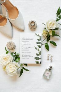 Wedding invitation flat lay with white roses and greenery. See more highlights from this Raleigh wedding on the blog.