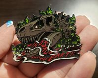 An original design featuring the T-rex fossil from THAT scene. Ya know. ;)  Hard enamel 2 rubber pin clutches 2 inches wide I do not own any rights or licenses. This is just for fun in the spirit of artist interpretation and craft.