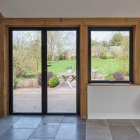 Aluminium doors in timber frames as part of a barn renovation in Somerset. The aluminium frames sit within timber frames on the barn renovation and give access to the large gardens. It is possible to install aluminium doors into timber frames if designed properly. These doors were installed and engineered by the team at IQ as part of a larger barn renovation and development. Click on the image to see more examples of this barn renovation and pictures of the aluminium doors in timber frames.