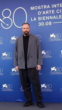 Yorgos Lanthimos wears a Lemaire workwear double breasted jacket with Officine Creative Lyndon 1 cut-out sandals during the photo call for his latest film 'Poor Things' at the 80th Venice Film Festival (2023)