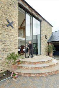 These glass doors are double height but - thanks to the high specification engineering - can be manually operated. The slim framed aluminium doors fill the old threshing barn doorway across a double height space. Click the image to read the full barn conversion case study. 