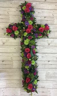 A striking, contemporary style floral cross for a coffin. Made up in bold, cerise roses, green chrysanthemums, hydrangeas, lisianthus, aspidistra leaves and leather leaf foliage.  #funeral #funeralflowers #religiousflowers #christiantribute #christiancross #holycross #floralcross #flowertribute #funeralflorist