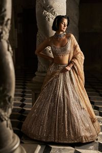 This lehenga set features all over mirror work and sequin embroidery in a linear pattern. The strappy blouse has crystal droplets at the waist. It is accompanied with a matching tissue organza dupatta.From Seema Gujral's Inara collection. DELIVERY TIMEPlease allow 8-12 weeks for your outfit to arrive. FABRIC DETAILSLehenga- Net, Blouse - Net, Dupatta - Tissue Organza Professional cleaning only.