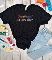 "The softest most comfy shirt for your favorite art teacher. This t-shirt features the wording \"Hooray! it's art day\". Hooray is in rainbow, and \"it's art day\" is printed in black or white depending on the color of the tee. (see photos) This t-shirt is the perfect gift for an elementary art teacher because the students get SO excited whenever it is their turn for art. Trust me I know - I am an elementary art teacher myself! 🎨 T-shirt sizes are Unisex, please refer to sizing chart in listing