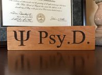 "\"PSI Symbol/PSY.D.\" Wood Block Sign. - Measures around 9 X 2.5 inches and .75 inch thick wood. - Laser engraved (deep wood indentation) - Sealed with Butchers Block Oil. - Made with real solid wood Makes A great PSYD graduation gift. Also, these are made to order and each sign is unique due to wood grain and engraving. Customize your sign with a Name, Special Message or both on back. Just send me a message of what you want engraved at checkout. (Please limit your special message to 15 words o