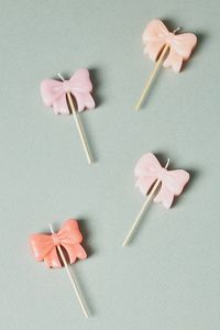 The Meri Meri Pink Bow Birthday Candles add a delightful pop of color and whimsy to any cake, turning every birthday celebration into a sweet and magical affair. | Pink Bow Birthday Candles, Set of 4 by Meri Meri, Cotton at Anthropologie