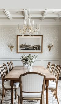 Take a look at this stunning dining room in a modern French country cottage estate. Decorated with vintage dining room furniture, classic wall sconces, a chandelier and modern art. Wallpaper in a dining room with French chandelier.