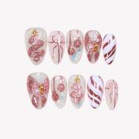 NAIL SHAPE: Short Almond APPROX. LENGTH: 13-18MM Under the Mistletoe by Ersa Nails brings holiday magic to your fingertips. With a delicate sheer white base and soft pink as the main color, this set is enhanced with dreamy glitter accents. Christmas tree, bow, and other festive motifs are thoughtfully placed throughout, while gold embellishments add a luxurious finish. This charming design perfectly captures the warmth and joy of the season, making it an ideal choice for celebrating the holidays