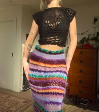 Crochet black mesh top using raglan stitch paired with a colourful crocheted long stripey skirt.