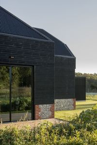 Architectural minimal framed glazing adds a stunning and contemporary look merging the original with the new sympatehtic flint and timber clad addition. Visit the website to read more on the architectural glazing to Black House Farm by Robin Lee Architecture.