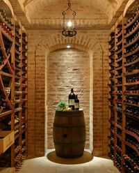 A small, but beautiful wine cellar in light brick. Wooden racks line both sides of the narrow room. A wine barrel serves as a tasting table. Designed by http://www.csceilings.ca/