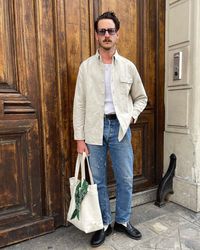 Clément Breton for Brut Clothing in a white jacket, mid-wash jeans, white socks, and penny loafers. Oh, and a tote bag!