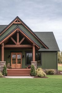 Modern rustic small barn home with board and batten forest green siding natural wood stain trim porch with beams and steps lawn with shrubs. Experience the cozy and rugged beauty of rustic homes that make modern architecture charming and personal.