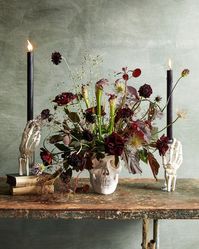 Floral Skull and Skeleton Hands Centerpiece | Looking for a festive floral arrangement for your Halloween party? This elegant (and spooky!) floral centerpiece, full of rich, dark colors is placed in a skull for a truly festive arrangement.  #halloween #homedecor #marthastewart #halloweendecor