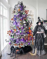 25 Halloween Trees that Will Convince You to Put Your Christmas Tree Up Today - Spooky Jam-Packed Halloween Tree - This spooky tree is jam-packed with ornaments, ribbons, spiders, and skeleton while a creepy life-sized doll stands watch.