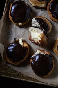 Keto boston cream donuts with a chocolate glaze and custard filling freshly baked on a baking tray