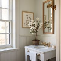 A small farmhouse cottage bathroom with cream vanity, cream shiplap paneled walls, natural oak bathroom mirror, vintage gold fixtures, and farmhouse decor. Design: @windthekey Follow @windthekey for more design inspiration.