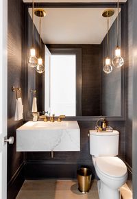 Black grasscloth wallpaper in the powder bath + floating marble vanity + brass fixtures and accents + large mirror behind the vanity and toilet | Tamara Magel