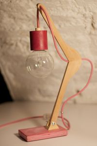 Lampada realizzata riutilizzando una gruccia in legno. La base é in cemento pigmentato e il portalampada é realizzato con un tubo di cartone. Ogni