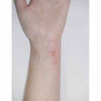 Tiny red heart tattoo located on the wrist,