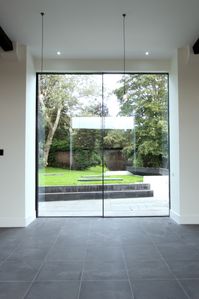 Threshing barn replacement doors in glass. The sliding glass doors replace the existing threshing barn doors with a minimal glass profile. The 4m tall sliding doors fill the barn door opening with glass for a minimal design. Click the image to see the full case study. 