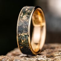 Introducing The Shenandoah, a handcrafted gold ring inlaid with authentic deep green Moss Agate gemstones and gold flakes in our signature wide channel inlay ring style. Designed for those who want a unique wedding band embedded with organic and natural elements from our recycled gold to the deep and distinctive green of moss agate. Each high-quality ring is handmade to order with precision and care by our artisans in North Carolina. The Shenandoah Gold Ring Features: SCS certified 100% recycled gold ring base Natural Moss Agate ring inlay with gold flakes Fit: Comfort Fit Finish: Polished Available in: 10K, 14K & 18K Yellow, Rose & White Gold Available Widths: 3mm, 4mm, 5mm, 6mm, 7mm, 8mm Free size from home kit available* Handcrafted to order in the USA Limited Lifetime Warranty Moss Aga