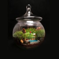 A beautiful clear glass apothecary jar is the perfect shape to showcase this hiking scene from all angles. A miniature hiker is shown trekking along a mossy landscape and stopping to pause near a beautiful crystal blue lake. This terrarium comes complete with fresh, live moss, river rocks, miniature hiker, artificial water feature and petrified wood pieces.