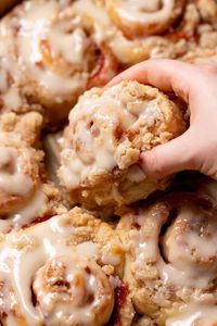 Peach cobbler cinnamon rolls are a Southern twist on a traditional cinnamon rolls recipe! These homemade cinnamon rolls are filled with peach jam and topped with a cinnamon crumb. Serve them with a scoop of vanilla ice cream for the ultimate summer dessert! | Cambrea Bakes