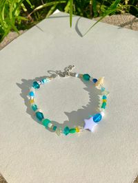 This anklet features assorted blue and complimentary color glass beads and a baby blue star on stretch cord with silver closure