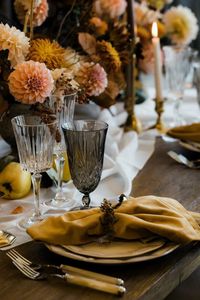 Autumn floral Thanksgiving table details place setting with brown water glass and yellow velvet napkin.