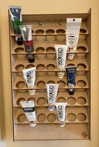 "Our wall mounted hobby paint storage racks are perfect for organizing your hobby paints and getting your hobby area ready for some serious use.  The paint storage shelves are set at an angle to save space and allow the racks to hold more.  Each rack also has a flat top shelf for storing other items such as glue, odd sized containers, or painted minis waiting to dry.  Each shelf has two pre-cut holes for mounting. Paint Storage Capacity - 42 Paint Tubes - sized for the 50ml tubes.  Cutout is 1.3