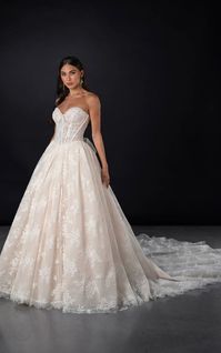 A fairytale romance comes to life, this lace ballgown wedding dress exudes romantic charm from every angle. Style 1847 features a strapless pearl-embellished sweetheart neckline atop a princess-inspired corset bodice. A charming laced back detail concludes with a delicate tulle bow to meet the classic Basque waist outlined in pearl beads. The romantic floral motifs cascade throughout the voluminous ballgown skirt that comes in both lined and unlined options, culminating in an exquisite eyelash lace trim at the hemline. This princess ballgown wedding dress brings the magic to that happily ever after moment.