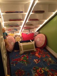 Under stairway reading space with rope lights and comfortable pillows.