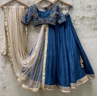 A three-piece peacock blue embroidered lehenga set from the Priti Sahni collection. This beautiful raw silk peacock blue lehenga with a zari border detail is paired with a sharmily sequin, beads & zardozi hand-embroidered blouse. The lehenga has side hanging ghungroo tassels to the waistline. And the blouse has a ghungroo tassel tie-up at the back. This outfit is completed with a beige sequined work net dupatta.