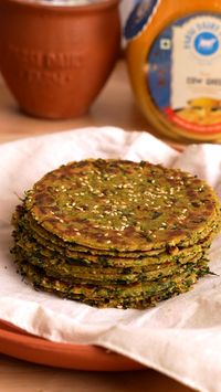 I recreated my Dadi’s Methi na Dhebra today, and it felt like a trip back to her kitchen!  Ingredients: - ½ cup Dahi - ¼ cup Jaggery chopped or powder - 2 cups Methi freshly chopped - 1 tsp Haldi - 2 tsp Ginger Green Chilli Paste - 1 tsp Green Garlic Paste - 1 tsp Ajwain - 2 tsp Sesame - ¼ tsp Hing - 3 tbsp Ghee - Salt to taste - 1 cup Bajra Flour - ¼ Cup Wheat Flour - Water as needed - Sesame seeds for sprinkling - Ghee for cooking