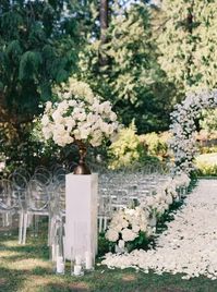 What a stunning outdoor summer wedding, a tall white floral arrangement on a white pillar greet guests at the aisle entrance and leads the eye down the white rose petal aisle.