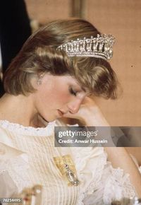 AUCKLAND, NEW ZEALAND - APRIL 29: Diana, Princess of Wales, wearing a cream satin dress by Gina Fratini with the Queen Mary Cambridge Lover's Knot Tiara and diamond earrings, looks tired as she attends a banquet on April 29, 1983 in Auckland, New Zealand.