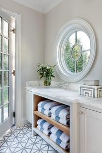 Feb 15, 2022 - Beautifully designed pool house features a round window located over towel cubbies topped with a honed marble countertop and fixed against white and gray mosaic floor tiles.