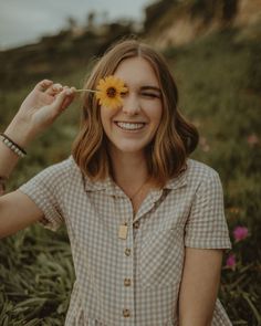 a woman smiles as she holds a flower in her hair