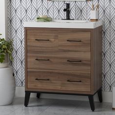 a bathroom vanity with drawers and a mirror on the wall next to a potted plant