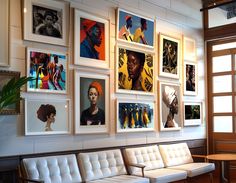 a living room filled with white couches and framed pictures on the wall above them