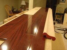 a wooden counter top in a room with chairs and a lamp on the floor next to it