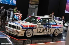 an old bmw race car on display in a showroom with people looking at it